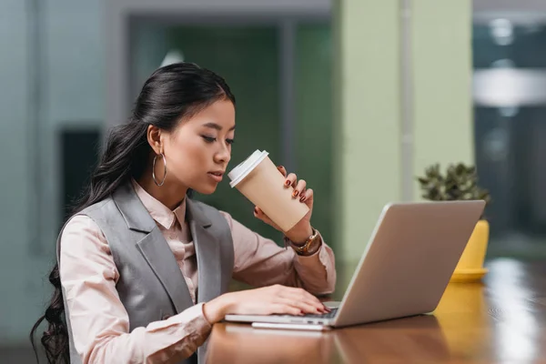 Joven asiático mujer de negocios trabajando con portátil y beber café - foto de stock