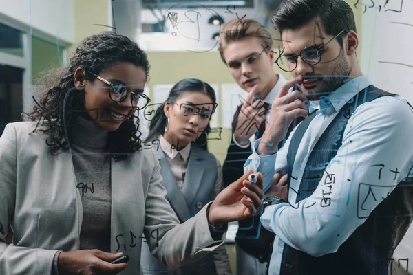 Multiethnic businesspeople working with glass board in office — Stock Photo