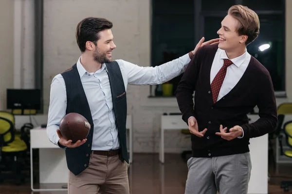 Молодые счастливые бизнесмены играют в регби в офисе — стоковое фото