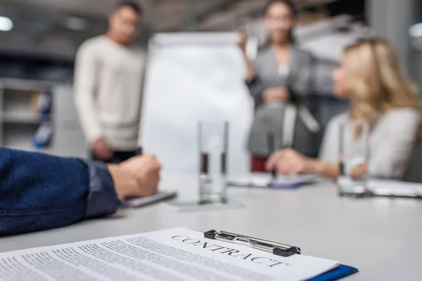 Business contract on table with blurred businesspeople on background — Stock Photo