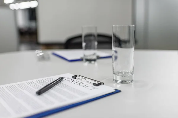 Contrato comercial en el portapapeles que pone sobre la mesa en la oficina - foto de stock