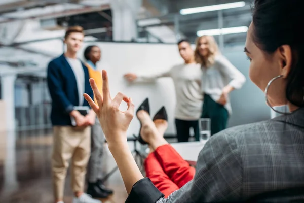 Manager machen Präsentation für Chefin, während sie Okay-Zeichen zeigt — Stockfoto