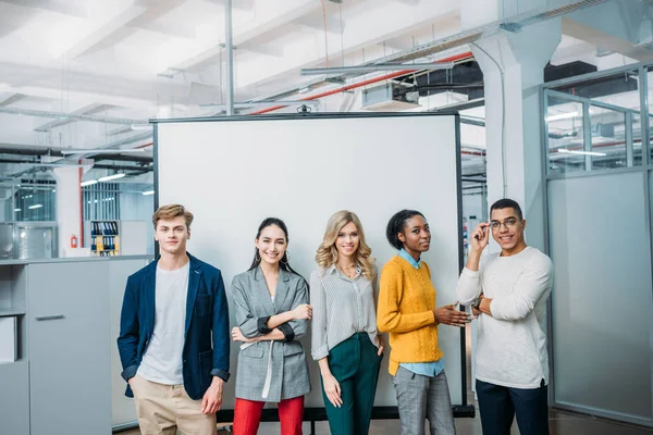 Group of young business partners standing in front of whiteboard — Stock Photo