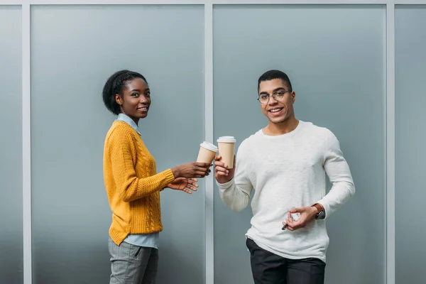 Jóvenes socios de negocios afroamericanos tintinear tazas de café desechables - foto de stock