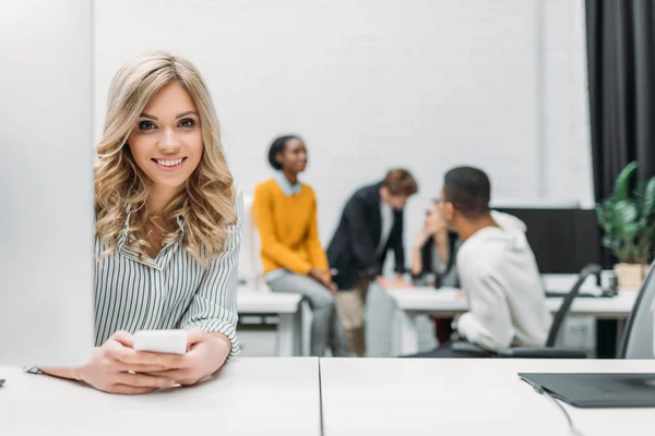 Young beautiful woman using smartphone at office — Stock Photo