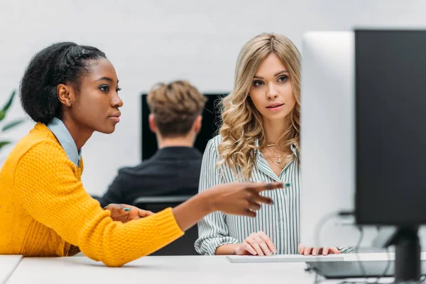 Jóvenes empresarias multiétnicas que trabajan juntas con el ordenador - foto de stock