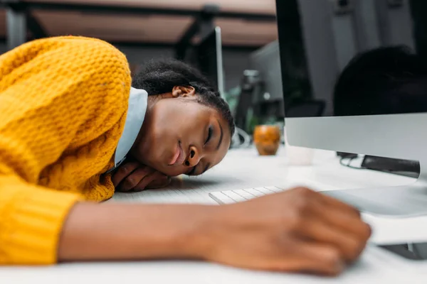Jovem afro-americana sobrecarregada dormindo no trabalho no escritório moderno — Fotografia de Stock