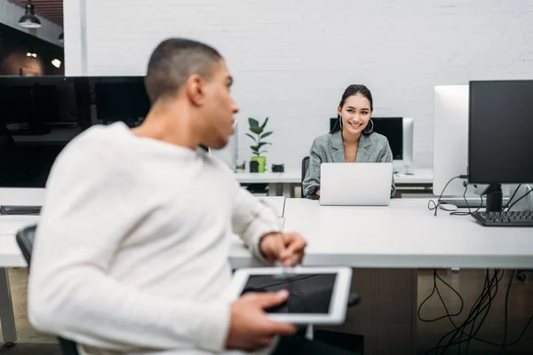 Socios empresariales jóvenes multiétnicos que hablan en la oficina - foto de stock