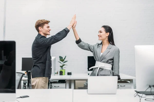 Socios comerciales multiétnicos que dan los cinco primeros en la oficina - foto de stock