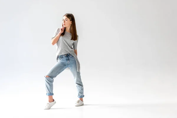 Jovem mulher elegante em jeans e camisa cinza olhando para a câmera, isolado em branco — Fotografia de Stock