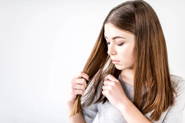 Retrato de mulher focada verificando o cabelo isolado no branco — Fotografia de Stock