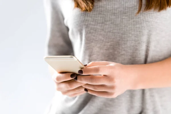 Recortado disparo de mujer sosteniendo teléfono inteligente en las manos, aislado en blanco - foto de stock