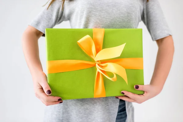 Partial view of woman holding wrapped present in hands isolated on grey — Stock Photo