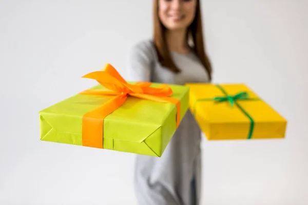 Selektiver Fokus einer lächelnden jungen Frau, die Geschenke in Händen zeigt — Stockfoto