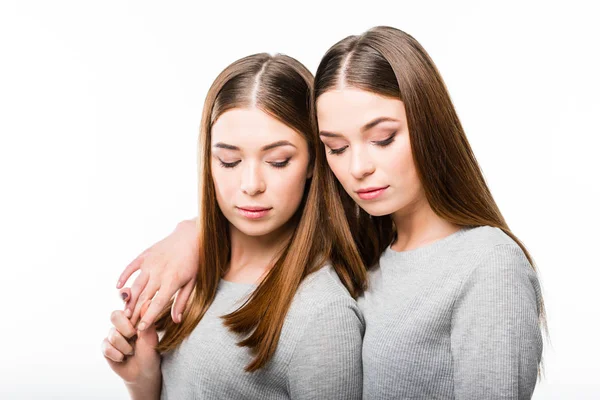 Retrato de hermanas gemelas atractivas mirando hacia abajo aisladas en blanco - foto de stock