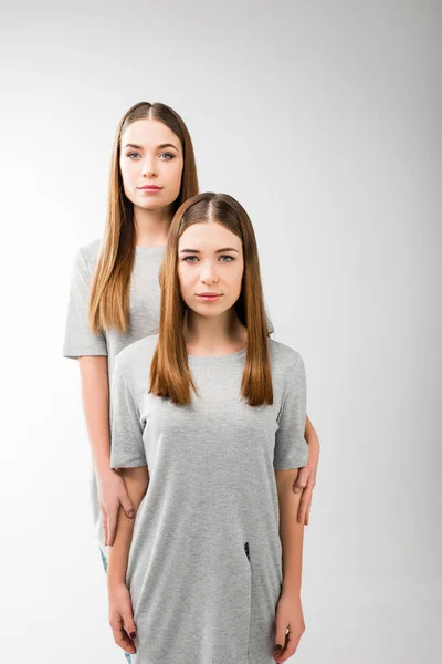 Portrait of young pensive woman hugging twin sister — Stock Photo