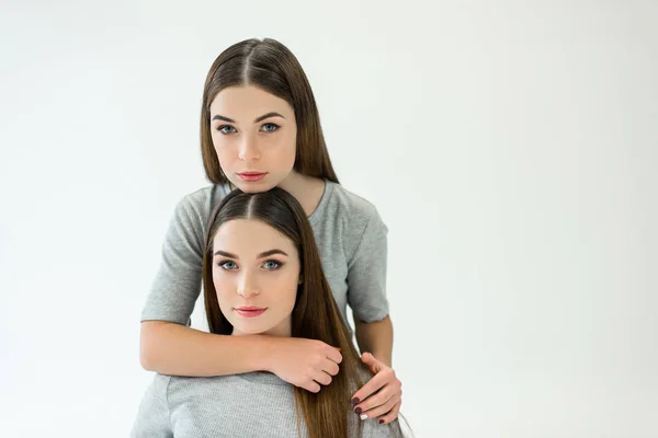 Porträt einer schönen Frau, die ihre Zwillingsschwester umarmt und in die Kamera blickt — Stockfoto
