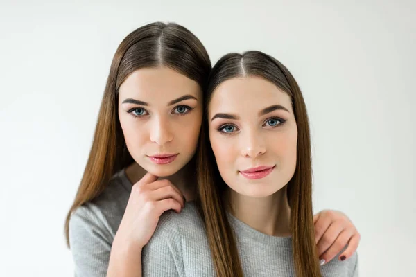 Porträt einer schönen Frau, die ihre Zwillingsschwester umarmt und in die Kamera blickt — Stockfoto