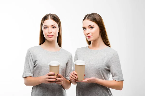 Портрет красивих близнюків з кавою, щоб йти в руки, дивлячись на камеру ізольовано на білому — стокове фото