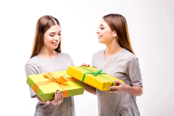 Porträt fröhlicher Zwillinge, die umwickelte Geschenke in Händen halten — Stockfoto