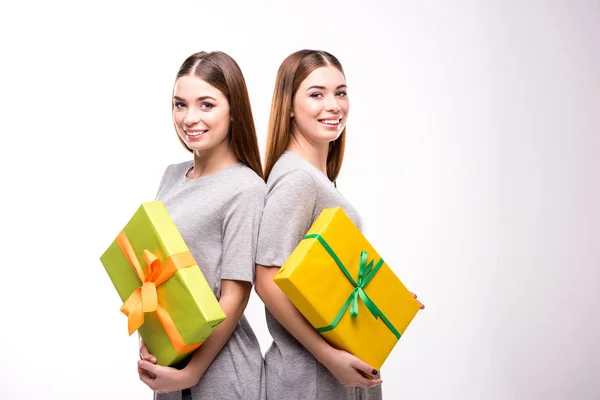Portrait of smiling twins with wrapped gifts in hands looking at camera — Stock Photo