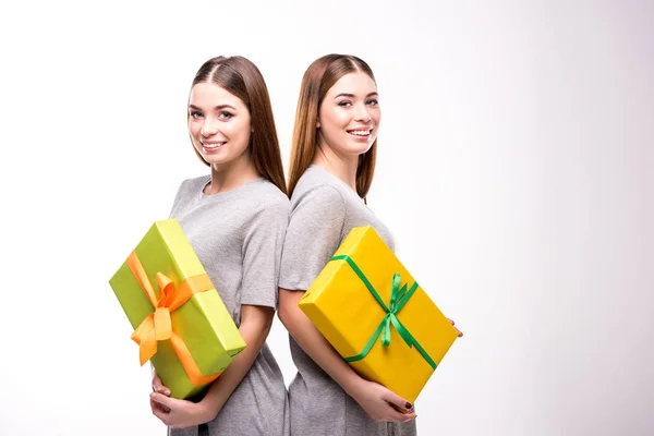 Retrato de gemelos sonrientes con regalos envueltos en las manos mirando a la cámara - foto de stock