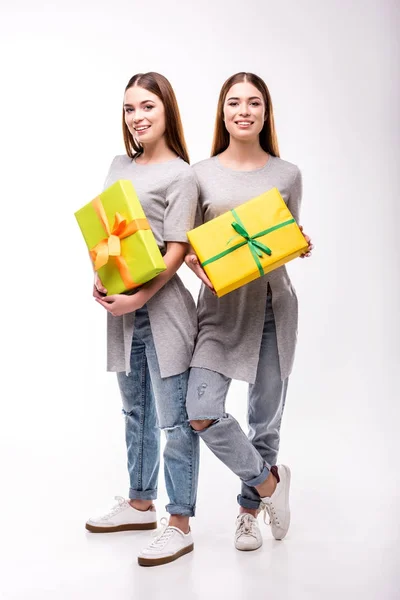 Lächelnde Zwillinge mit eingewickelten Geschenken in den Händen, die in die Kamera schauen — Stockfoto