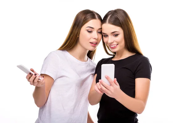 Portrait of beautiful twins with smartphones isolated on white — Stock Photo