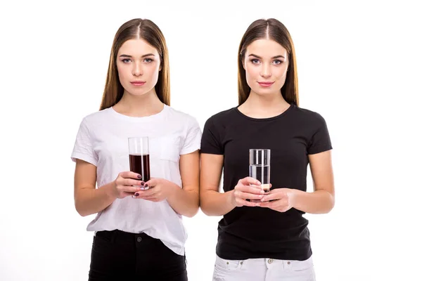 Portrait de beaux jumeaux tenant des verres de soda et d'eau dans des mains isolées sur blanc — Photo de stock