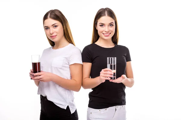 Retrato de hermosos gemelos sosteniendo vasos de soda y agua en manos aisladas en blanco - foto de stock