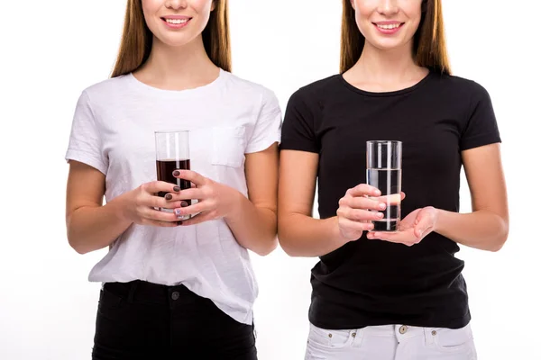 Vista parcial de mujeres sonrientes sosteniendo vasos de soda y agua en manos aisladas en blanco - foto de stock