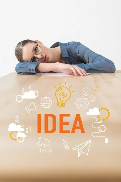 Tired businesswoman lying on table in office with idea inscription and business icons — Stock Photo