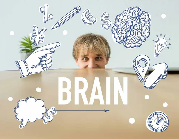 Man looking out from table and looking at camera with brain inscription and business signs — Stock Photo