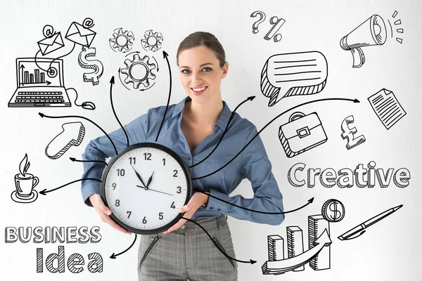 Smiling businesswoman holding wall clock in hands on white with creative business idea inscription and hand-drawn icons — Stock Photo