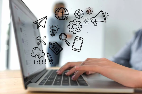 Imagen recortada de la mujer de negocios que trabaja con el ordenador portátil, iconos de negocios dibujados a mano - foto de stock
