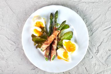 Fırında domuz pastırması ve haşlanmış yumurta ile pişirilmiş taze organik kuşkonmaz. Kapat, üst görünüm