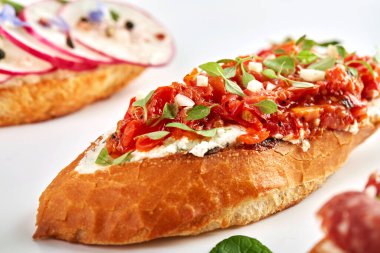 Domatesli, çilekli, avokadolu, turplu, peynirli ve jambonlu bruschetta. Beyaz bir arkaplanda, üst görünümde, yakın plan.