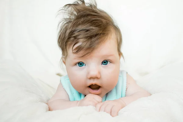 Blauwogige baby ligt op een zachte deken en Verheugen. — Stockfoto