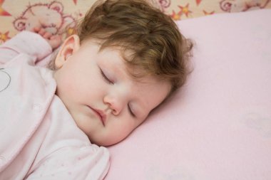 Küçük bir çocuk karyolasında uyuyor.