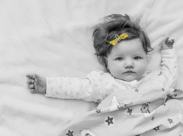 Uma criança pequena com um arco amarelo, fotografia em preto e branco . — Fotografia de Stock
