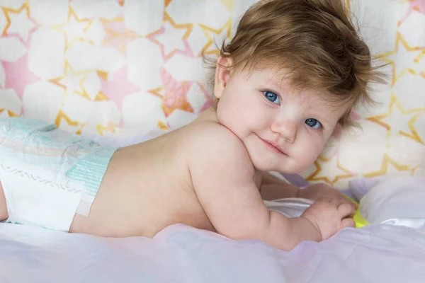 Bebé bonito em fraldas mentiras e sorrisos . — Fotografia de Stock