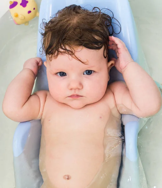 Kleine baby zwemt in de badkuip. — Stockfoto