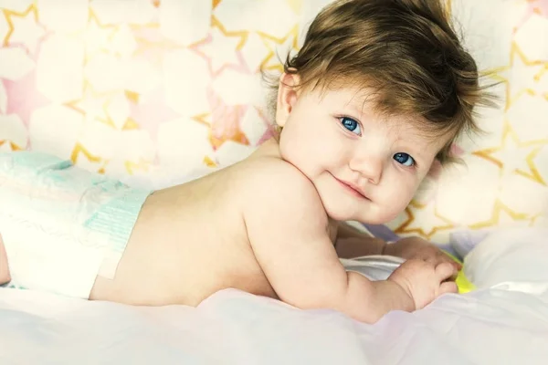 Bebé bonito em fraldas mentiras e sorrisos . — Fotografia de Stock