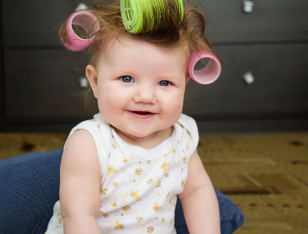 O bebê sorri com encrespadores no cabelo . — Fotografia de Stock