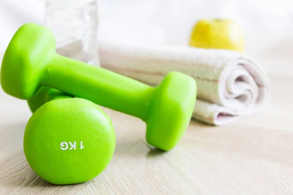 Groene halters, fles water, apple en een handdoek. Instellen voor sport. Het concept van de sport, een gezonde levensstijl. — Stockfoto