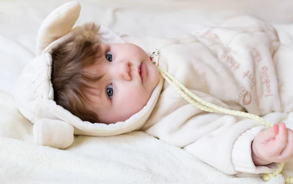 Pequeno bebê bonito em um traje engraçado com orelhas deitadas de costas . — Fotografia de Stock