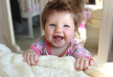 Yatağın duran küçük bebek gülüyor.