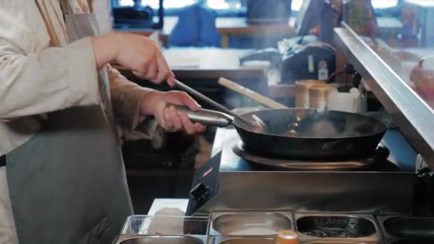 Koch rührt in Großküche Gemüse mit Fleisch im Wok — Stockvideo