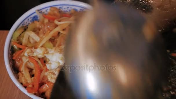 Kuchař dá čínských nudlí se zeleninou a masem v misce, zblízka Shot — Stock video