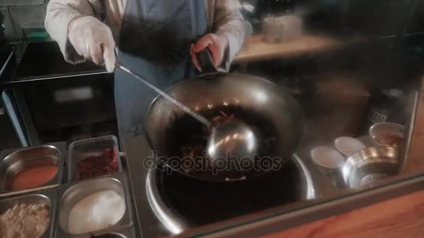 Шеф-повар перемешивает овощи с мясом в воке на коммерческой кухне, пан-азиатская кухня — стоковое видео